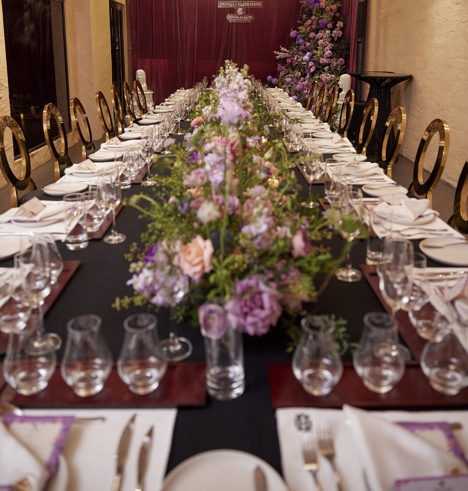Long banquet table with lilac flowers and crystal glasses
